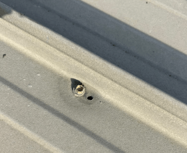 Damaged fastener point and small hole in commercial metal roof sheeting