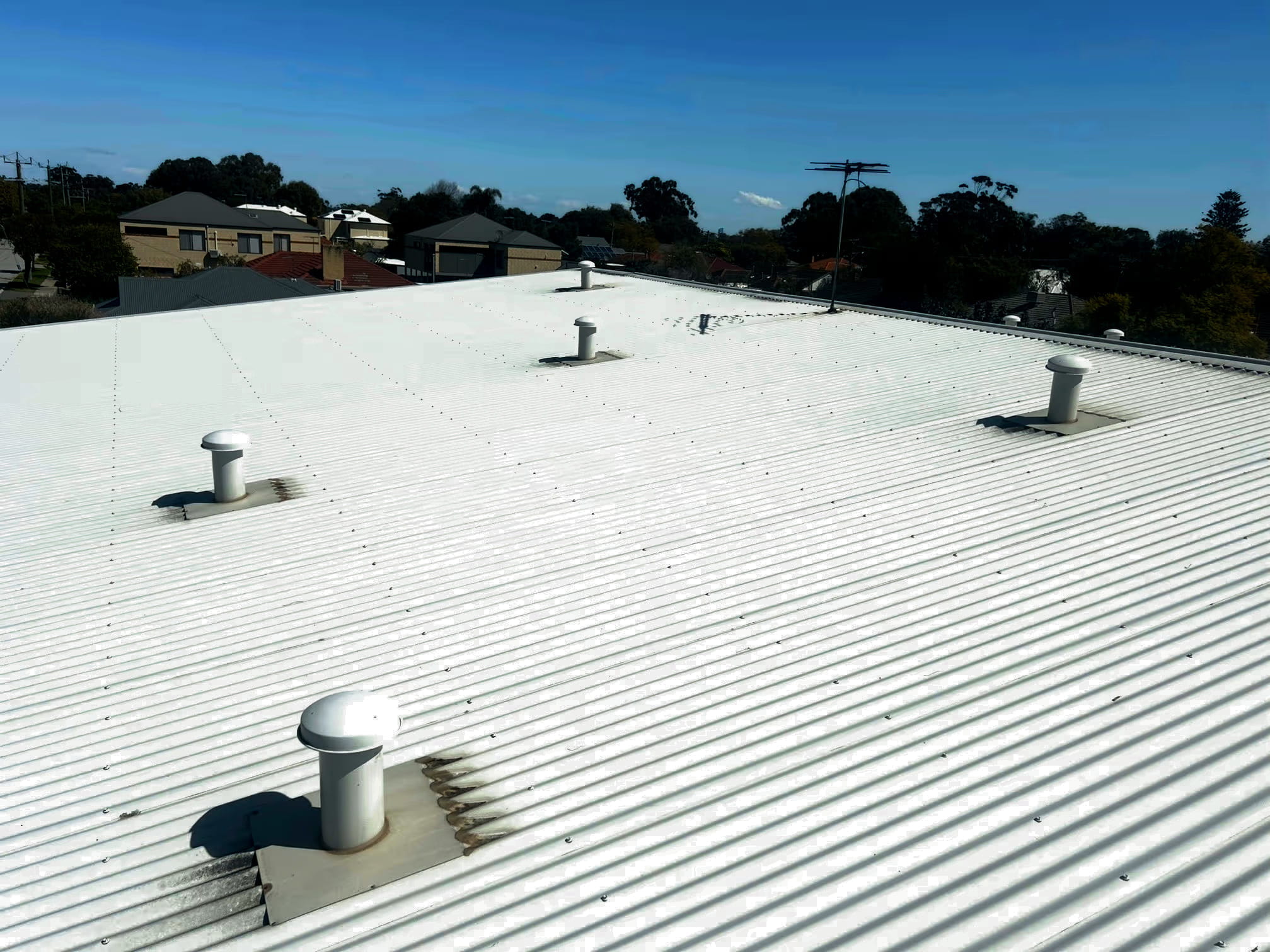 White metal commercial roof with multiple vents and roof penetrations