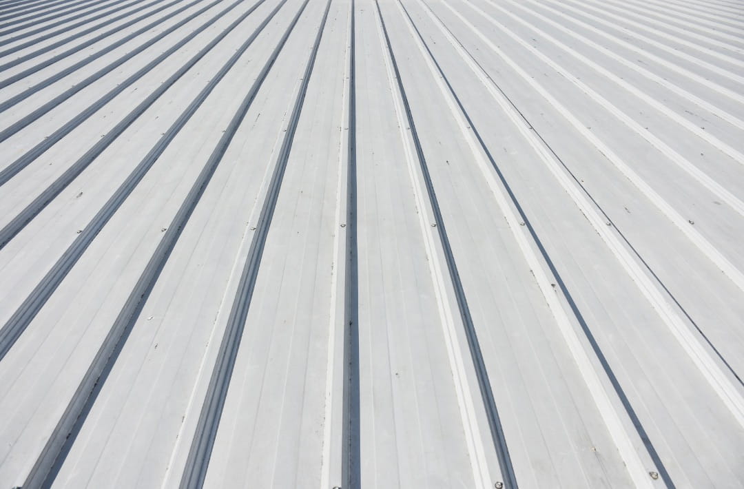 Metal roof sheeting on a commercial building showing long-run panels and drainage profile.