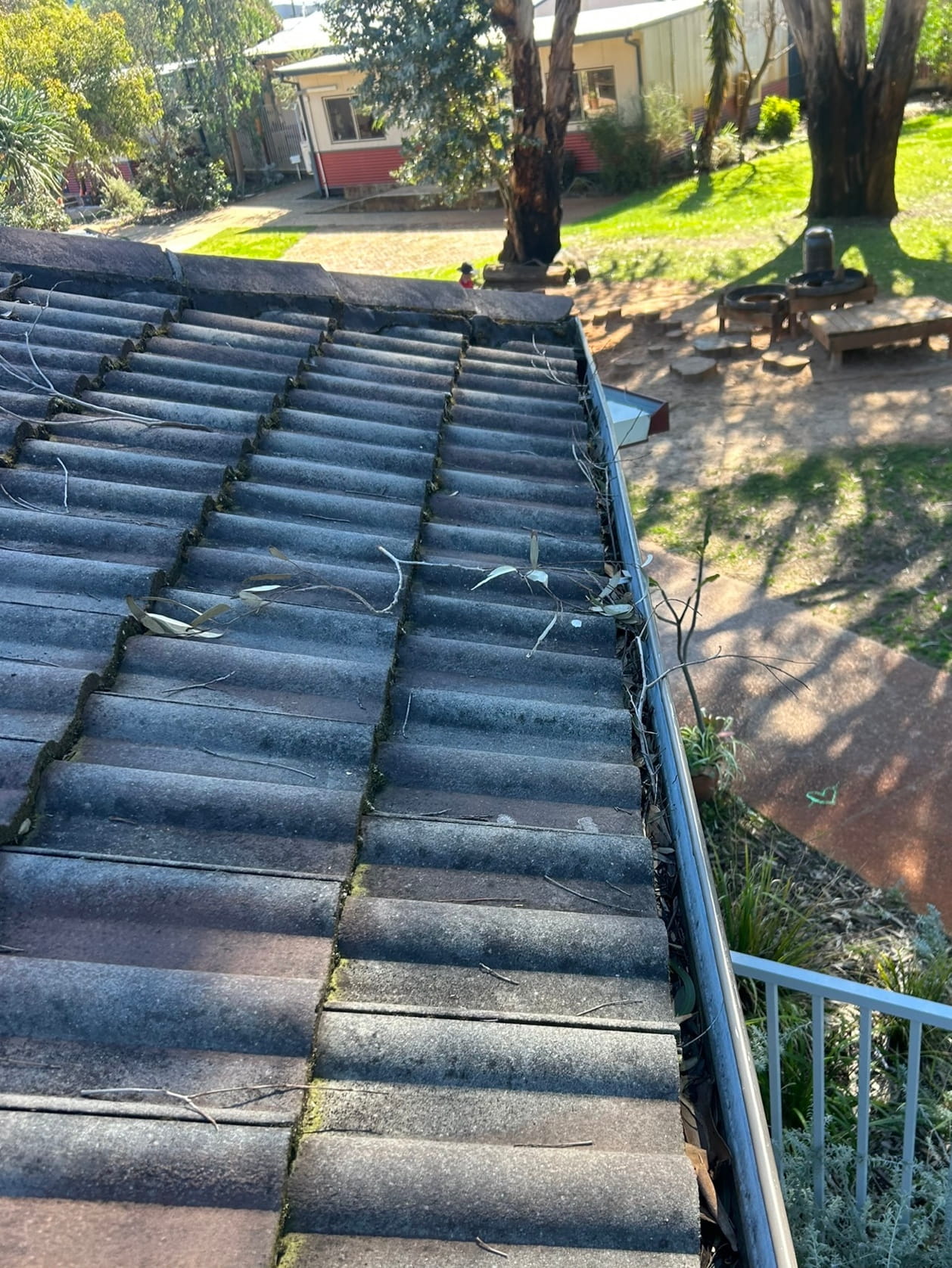 Eaves gutter on commercial building blocked with leaves, debris, restricting water flow.