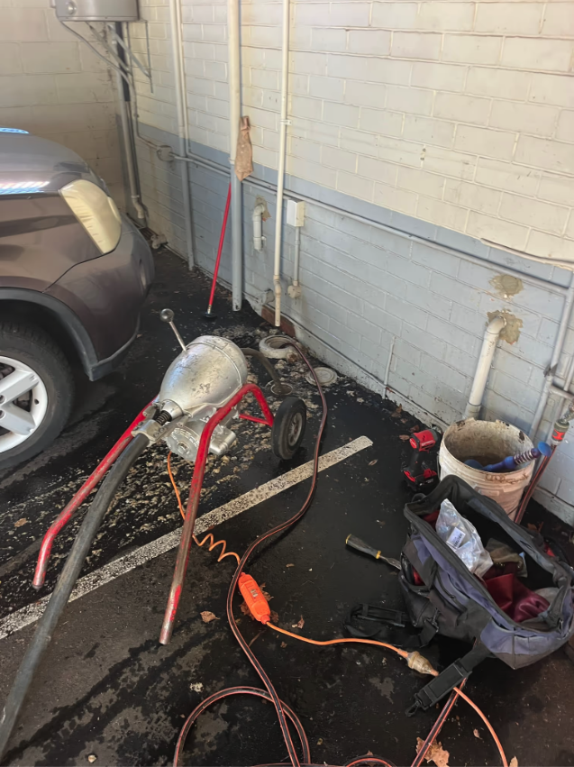 Drain clearing equipment set up beside an access point at a commercial property.