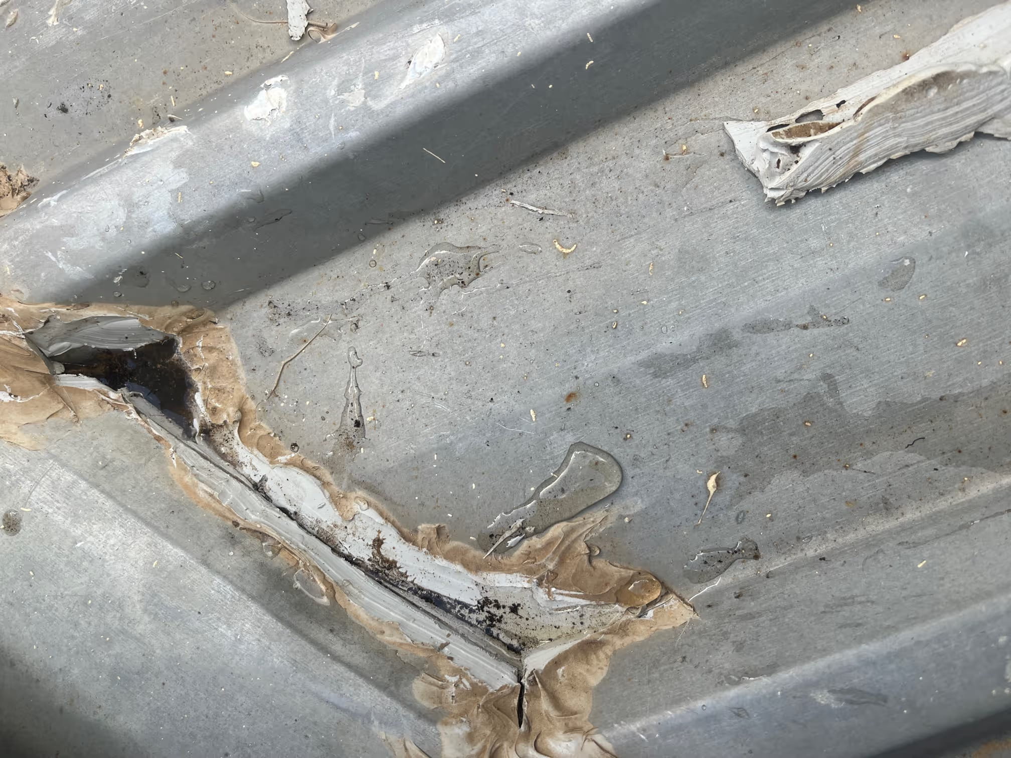 Close-up of previous sealant repairs to commercial metal roof sheeting.