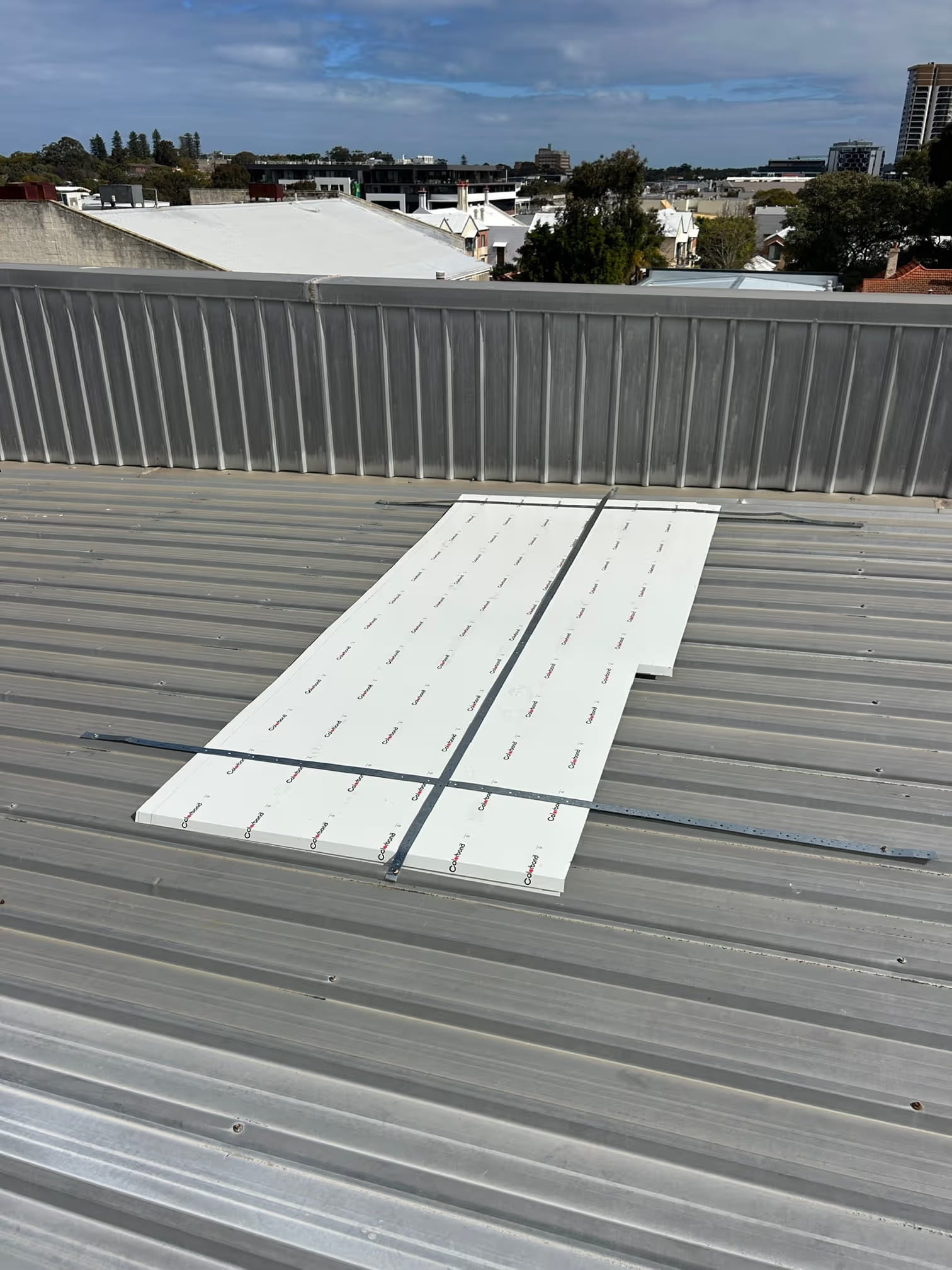Metal commercial roof with replacement roof sheets laid out ready for installation