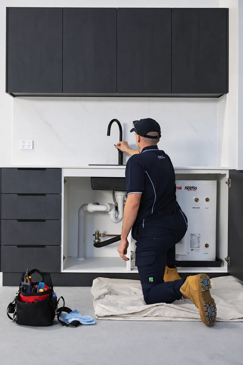 Plumber carrying out an under-sink plumbing repair